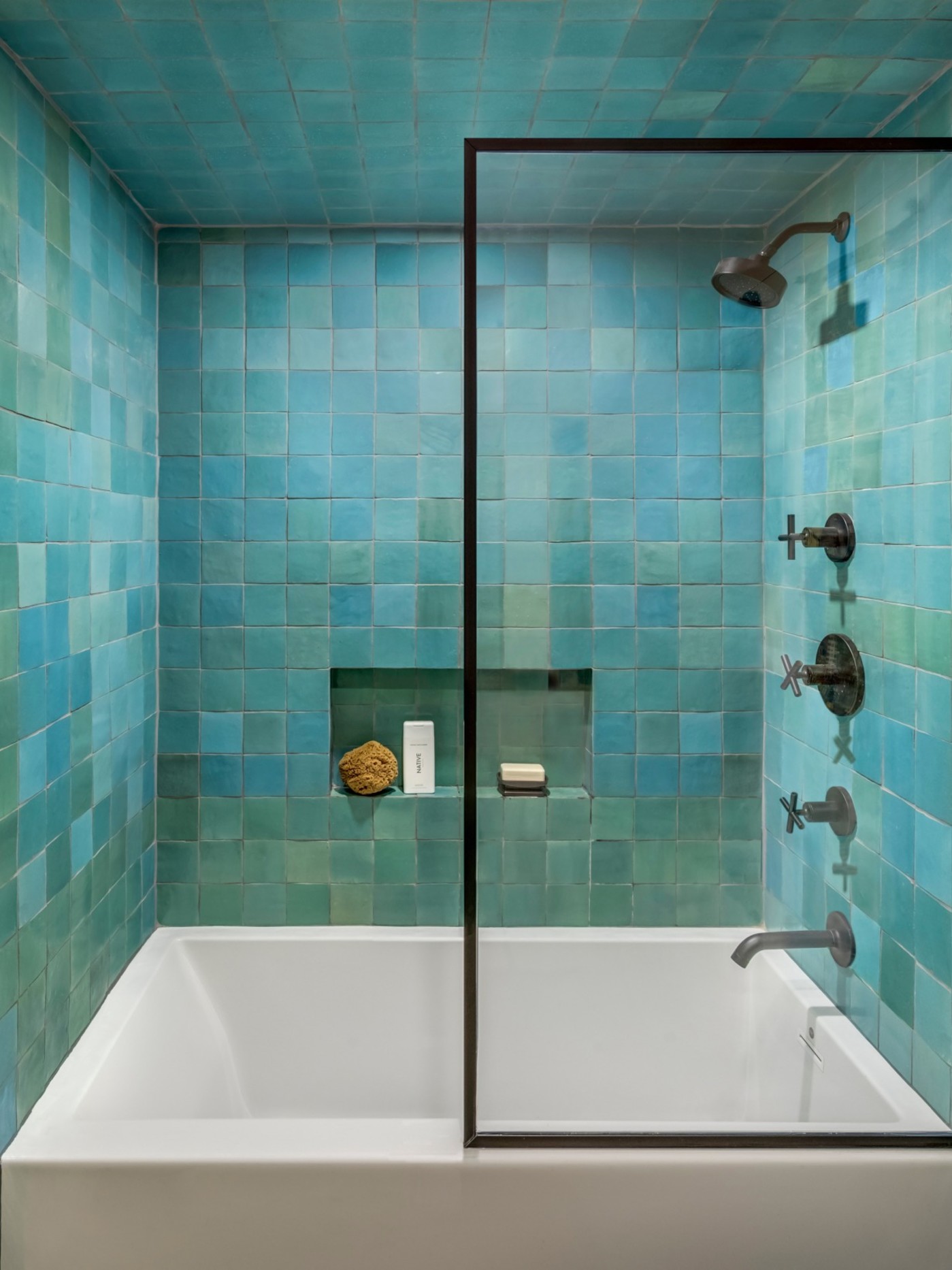 a bathtub and shower with blue tiled walls.