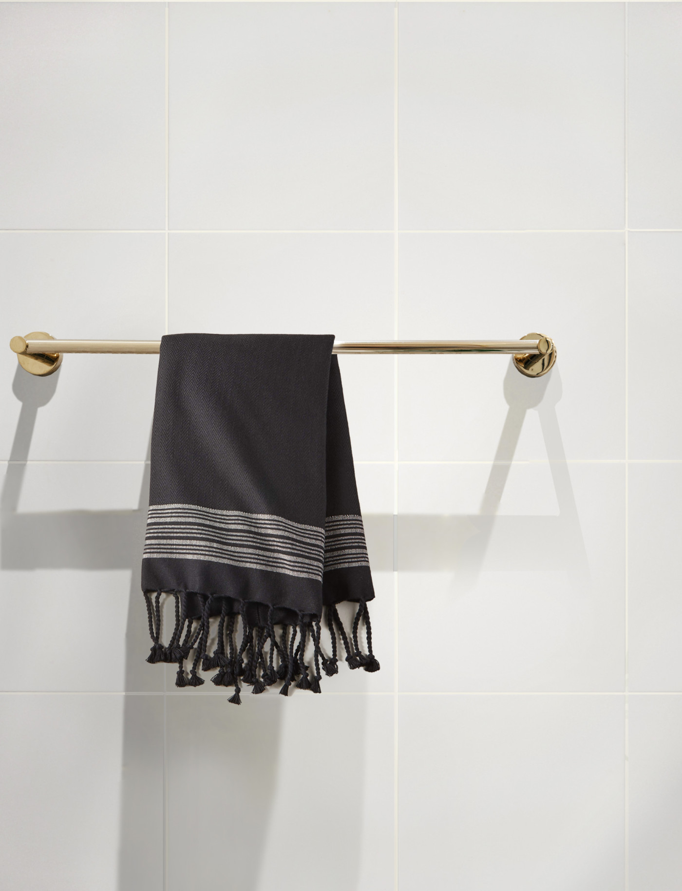 a black towel hangs on a towel rack in a white bathroom.