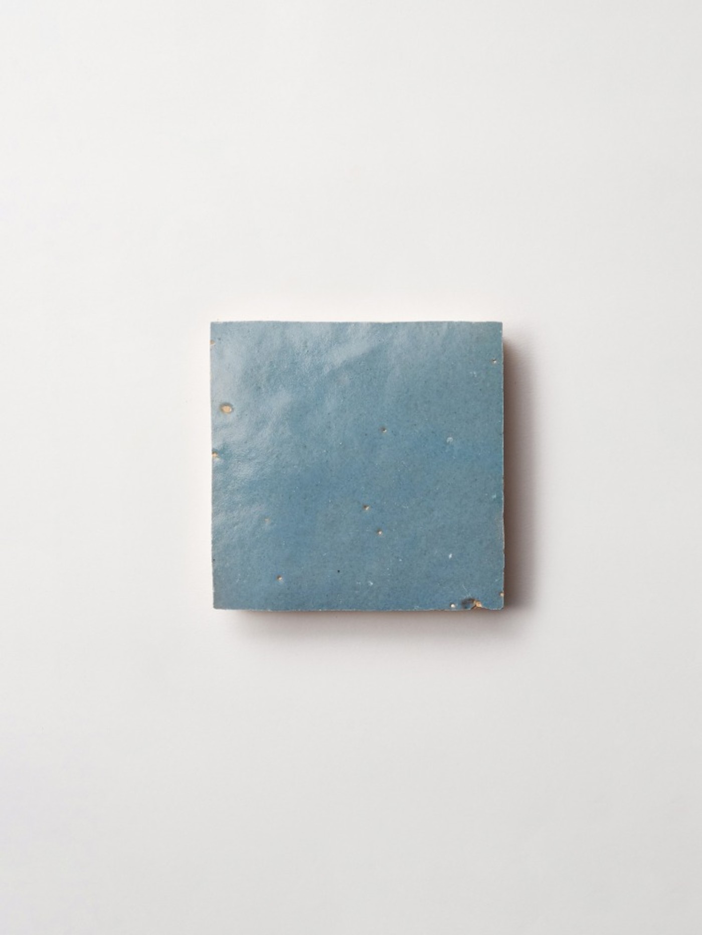 a blue square tile on a white background.