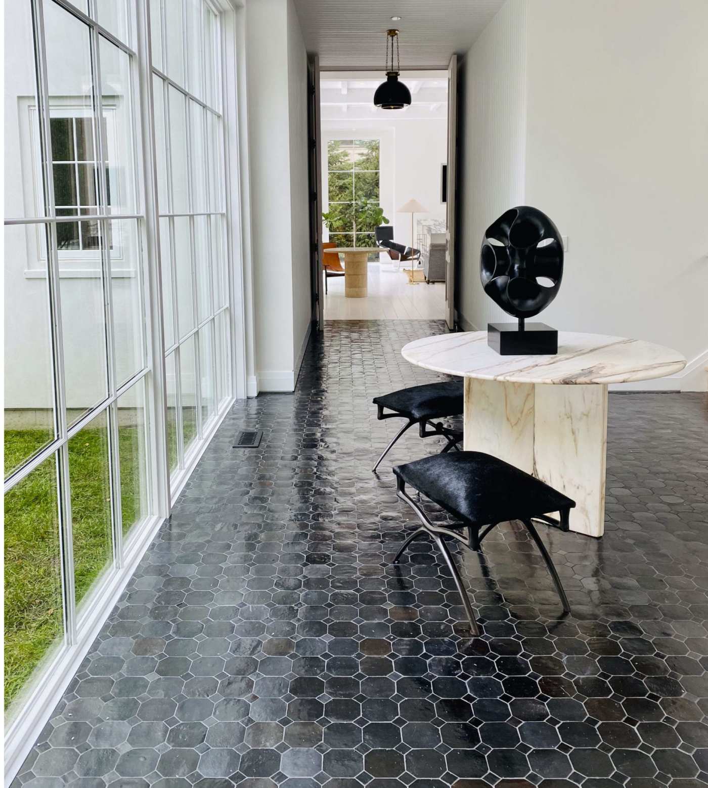 a black tiled room with floor-to-ceiling windows and a table and chairs.