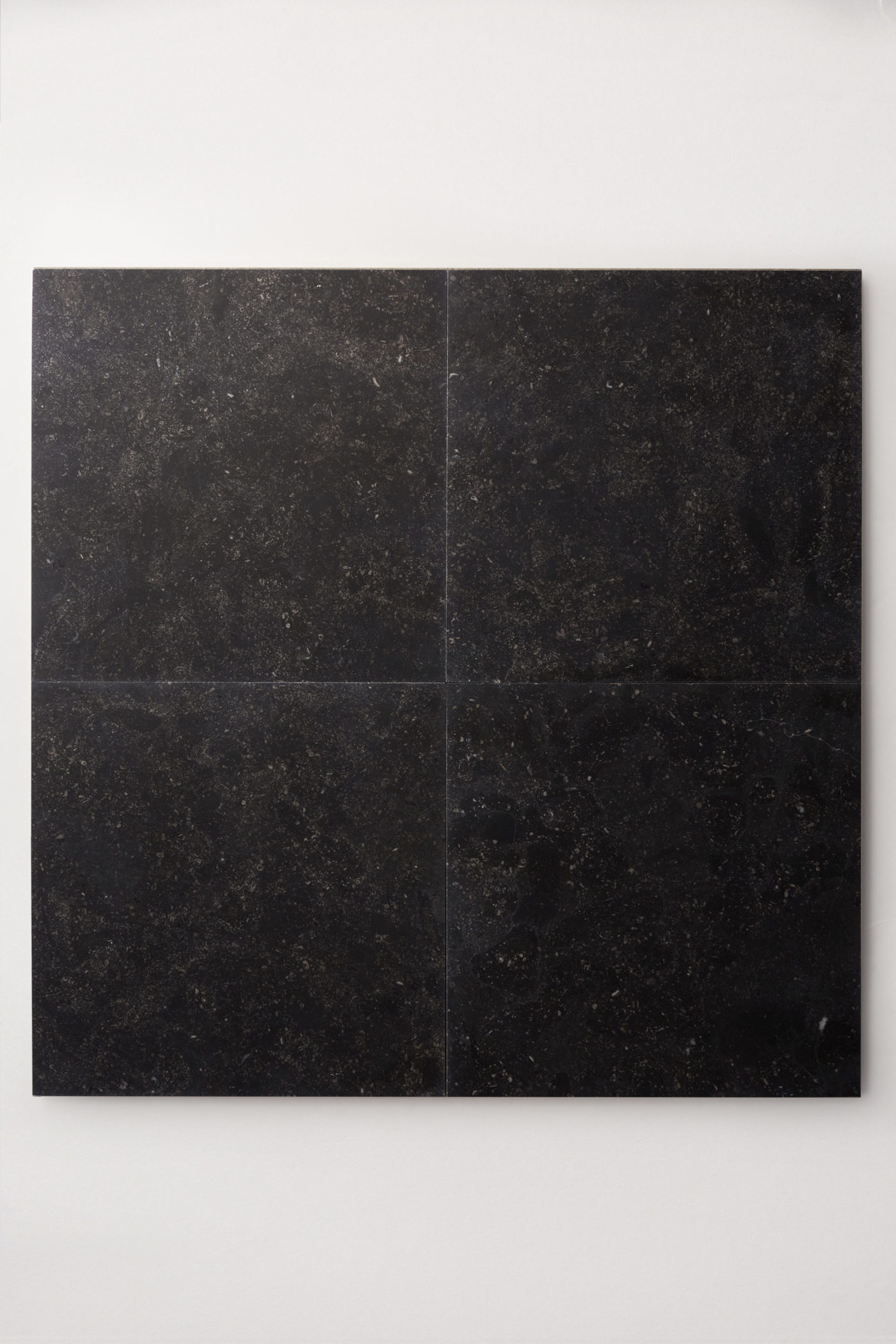 four square black limestone tiles on a white surface.