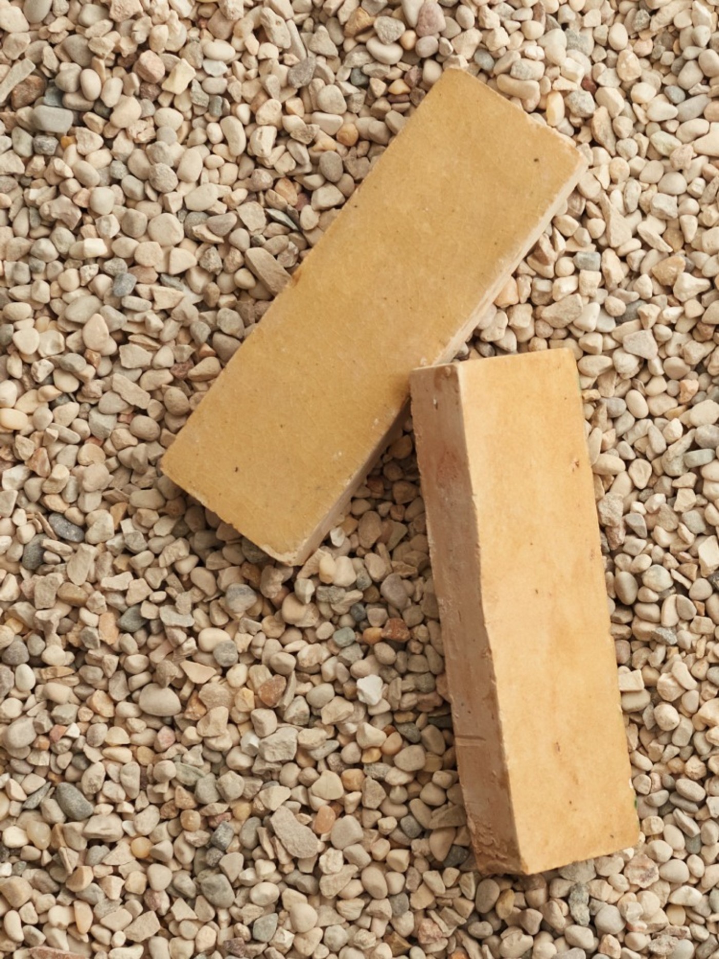 two yellow tiles on a gravel surface.