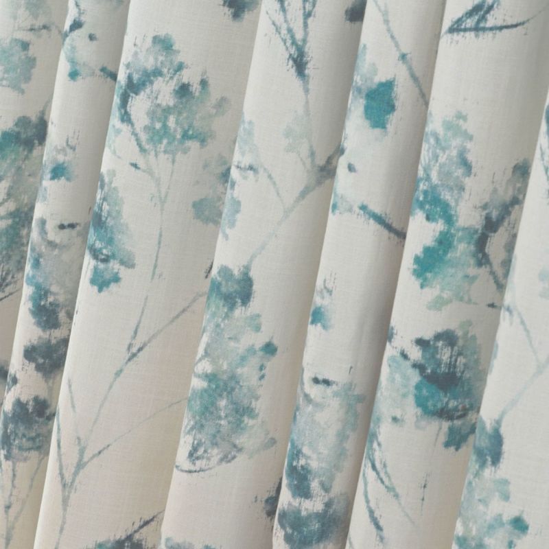 Fabric curtains with vertical pleats and teal watercolor floral print, hanging in soft folds; close-up interior view with neutral cream background and diffuse natural light.