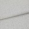 Light-gray, pebble-patterned upholstery fabric folded once, textured with a subtle metallic sheen; close-up view on a neutral surface under soft, diffuse lighting.