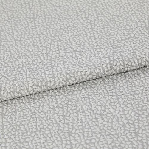 Light-gray, pebble-patterned upholstery fabric folded once, textured with a subtle metallic sheen; close-up view on a neutral surface under soft, diffuse lighting.