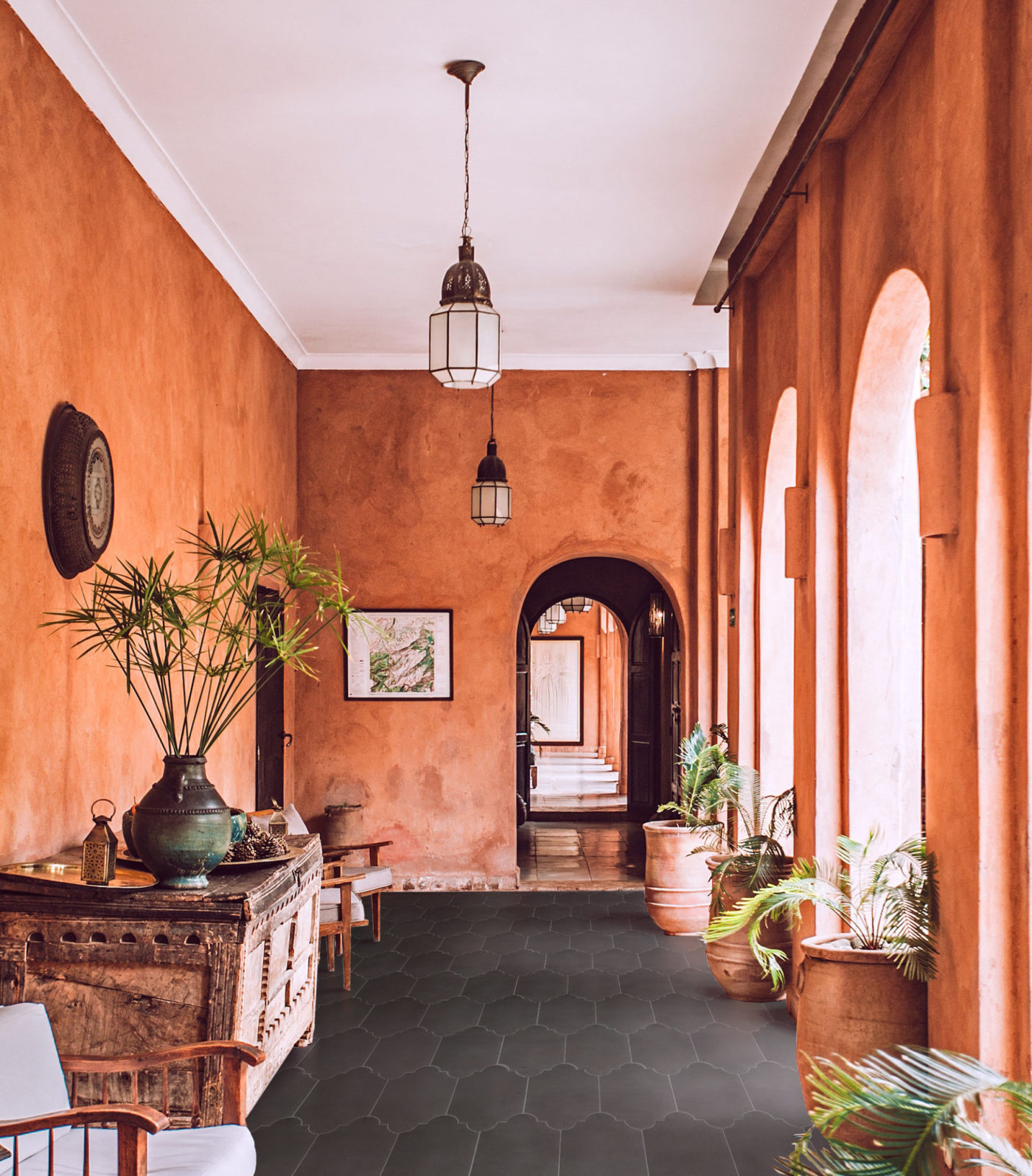 an orange hallway with a black tiled floor and potted plants.