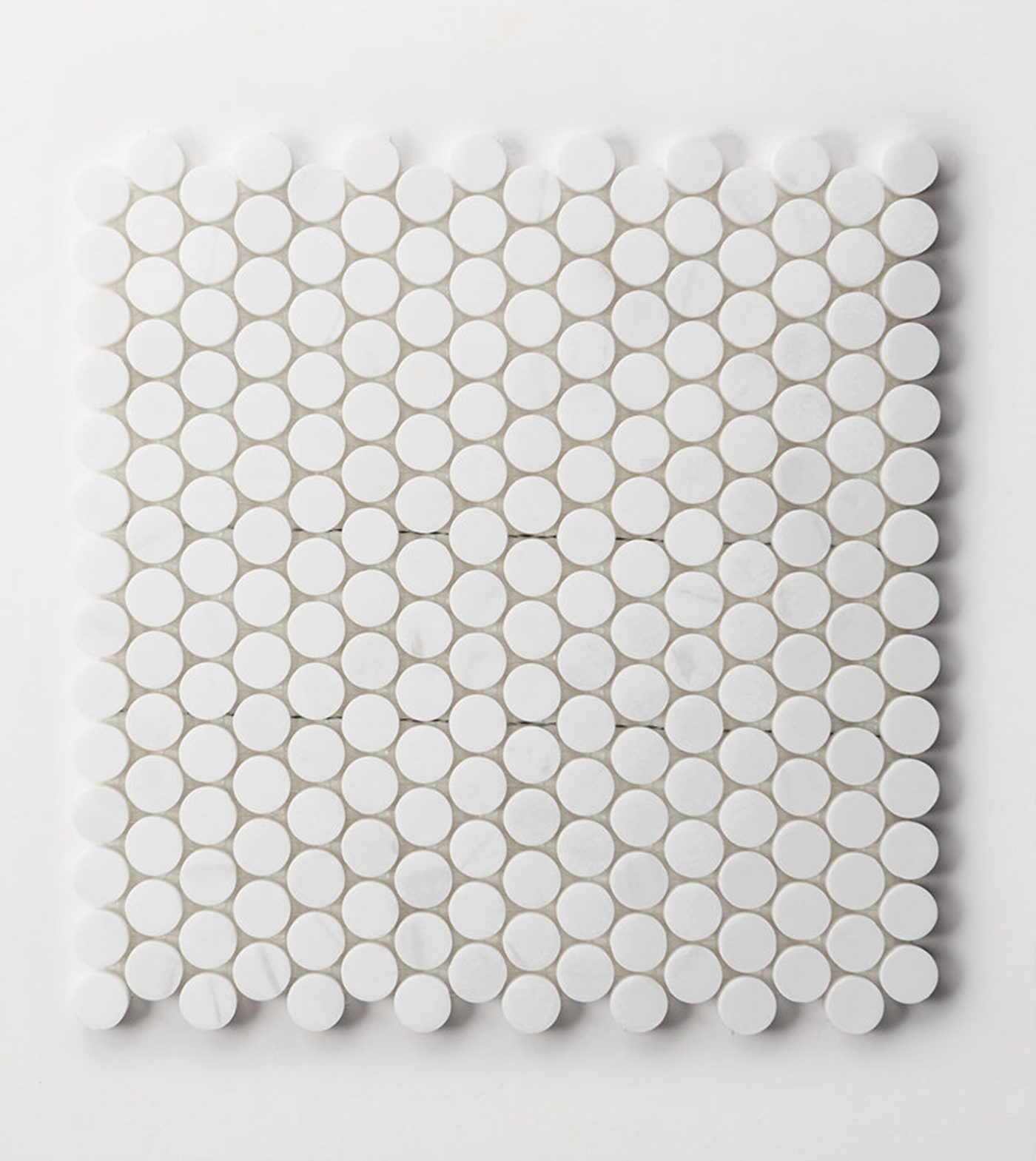 a sheet of small white penny shaped tiles on a white background.