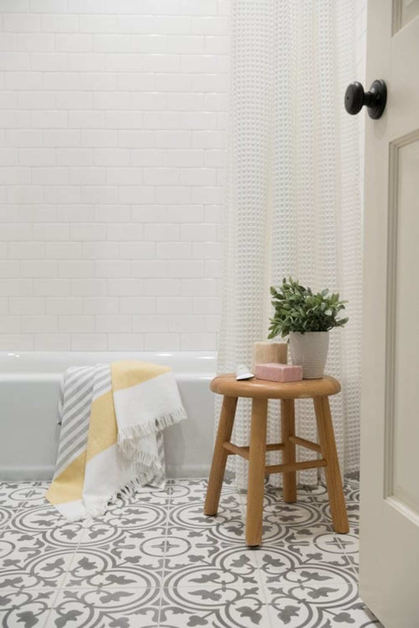 a bathroom with a stool and a black and white tile floor.