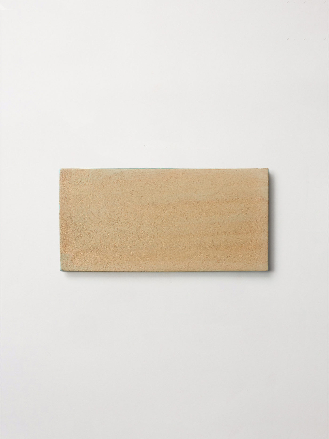 a tan tile hanging on a white wall.