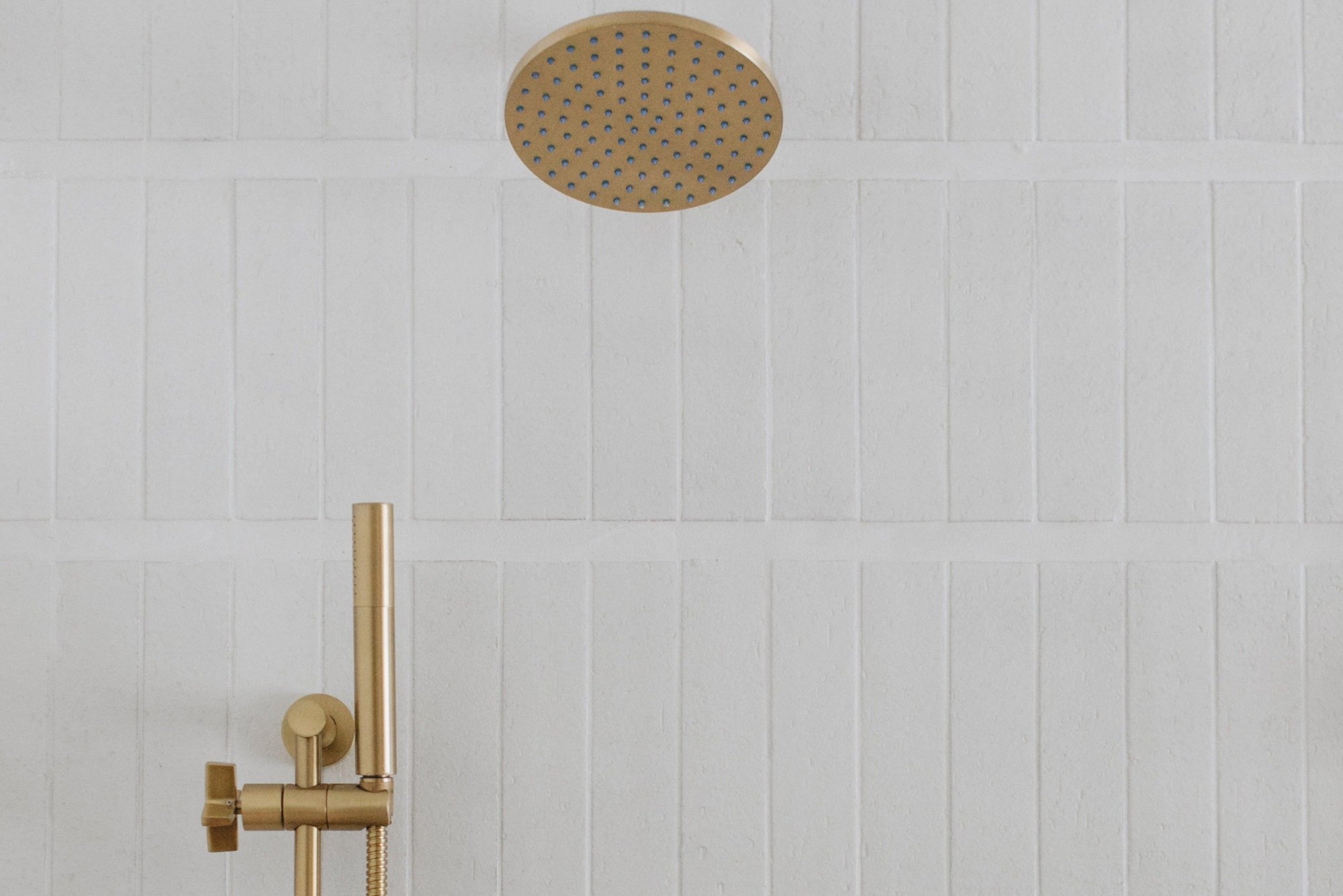 a gold shower head and a white wall.