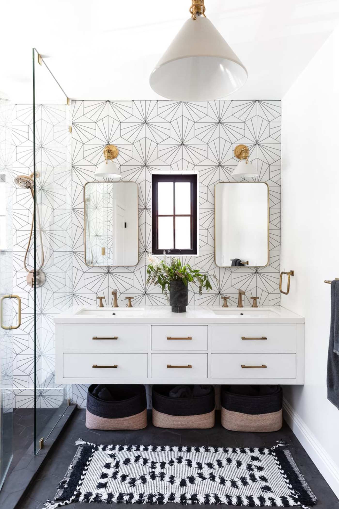 a bathroom with black and white tiles and a rug.