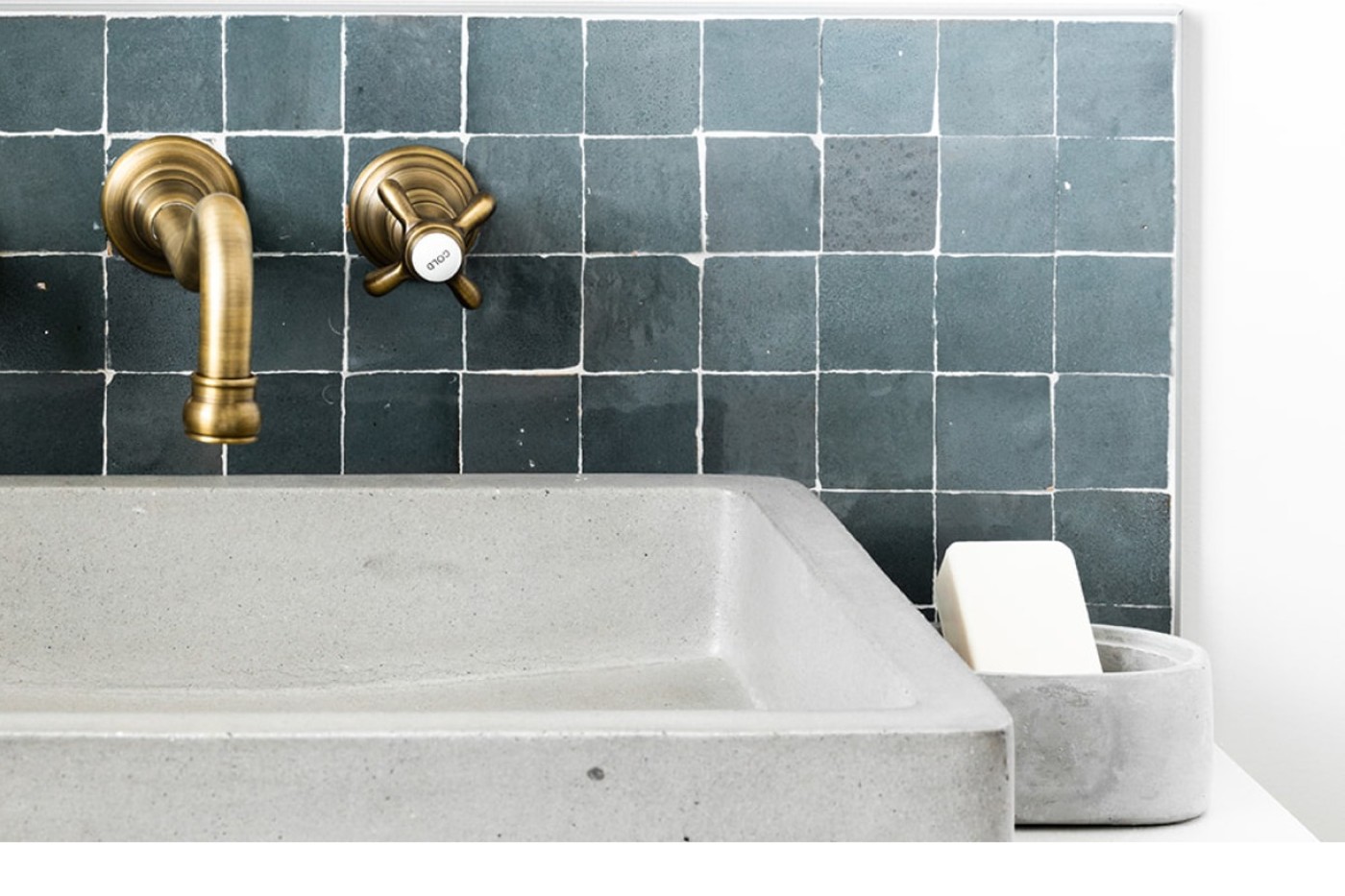 a bathroom sink with a brass faucet and blue tile backsplash.