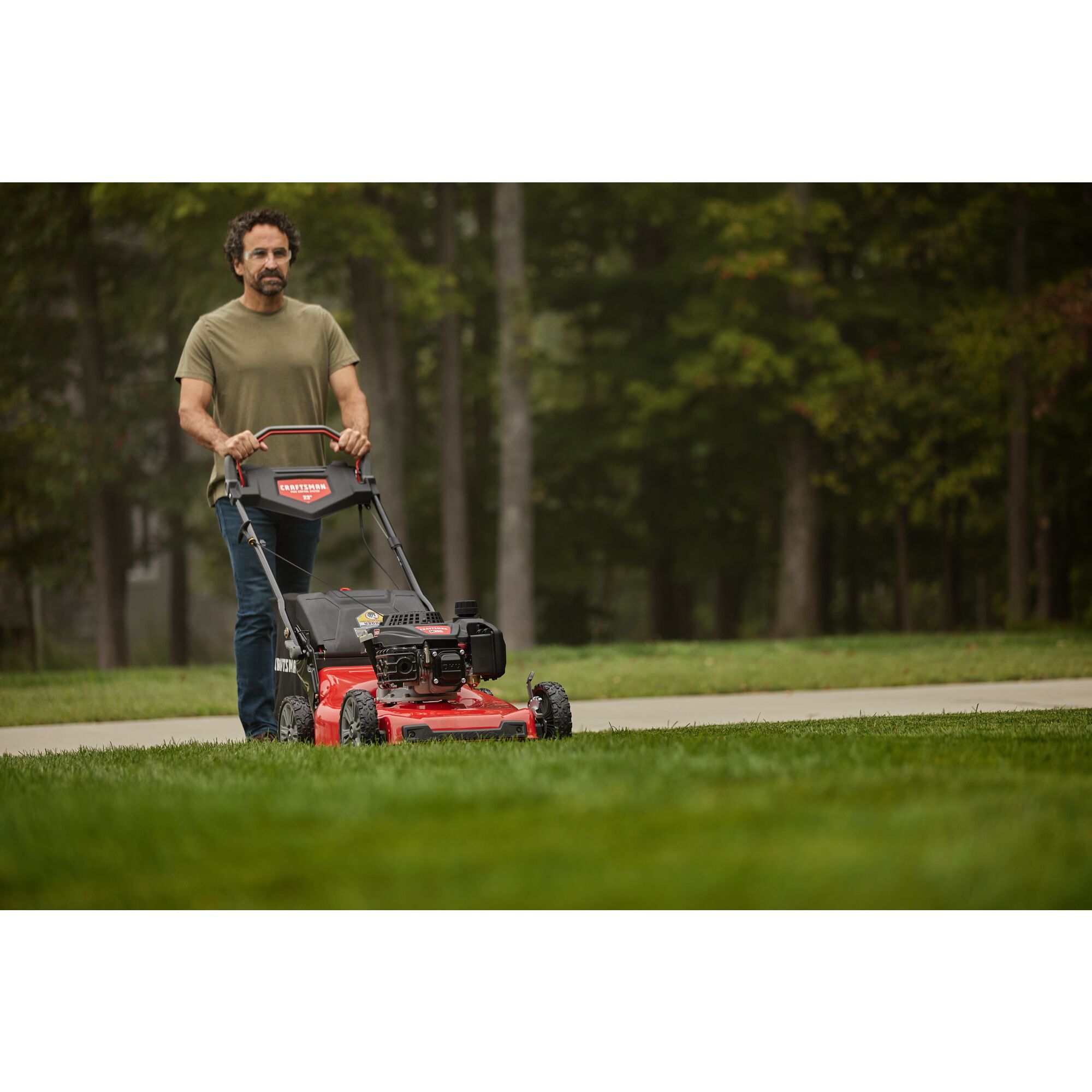 CRAFTSMAN M355 Self Propelled Lawn Mower in front view mowing a wooded lawn with green shirt
