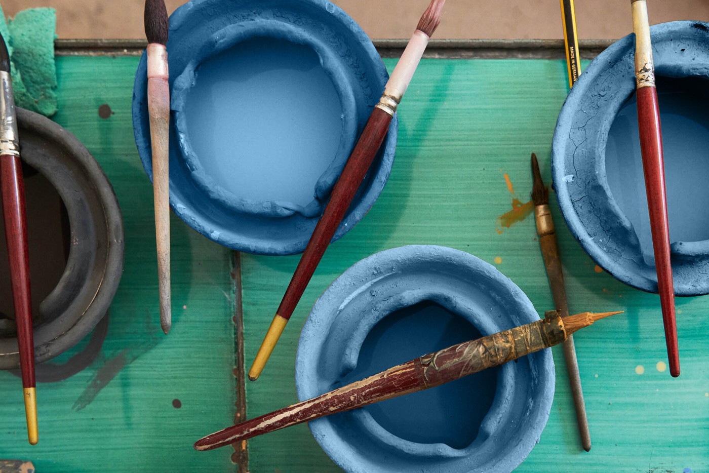 a group of paint brushes and bowls on a table.