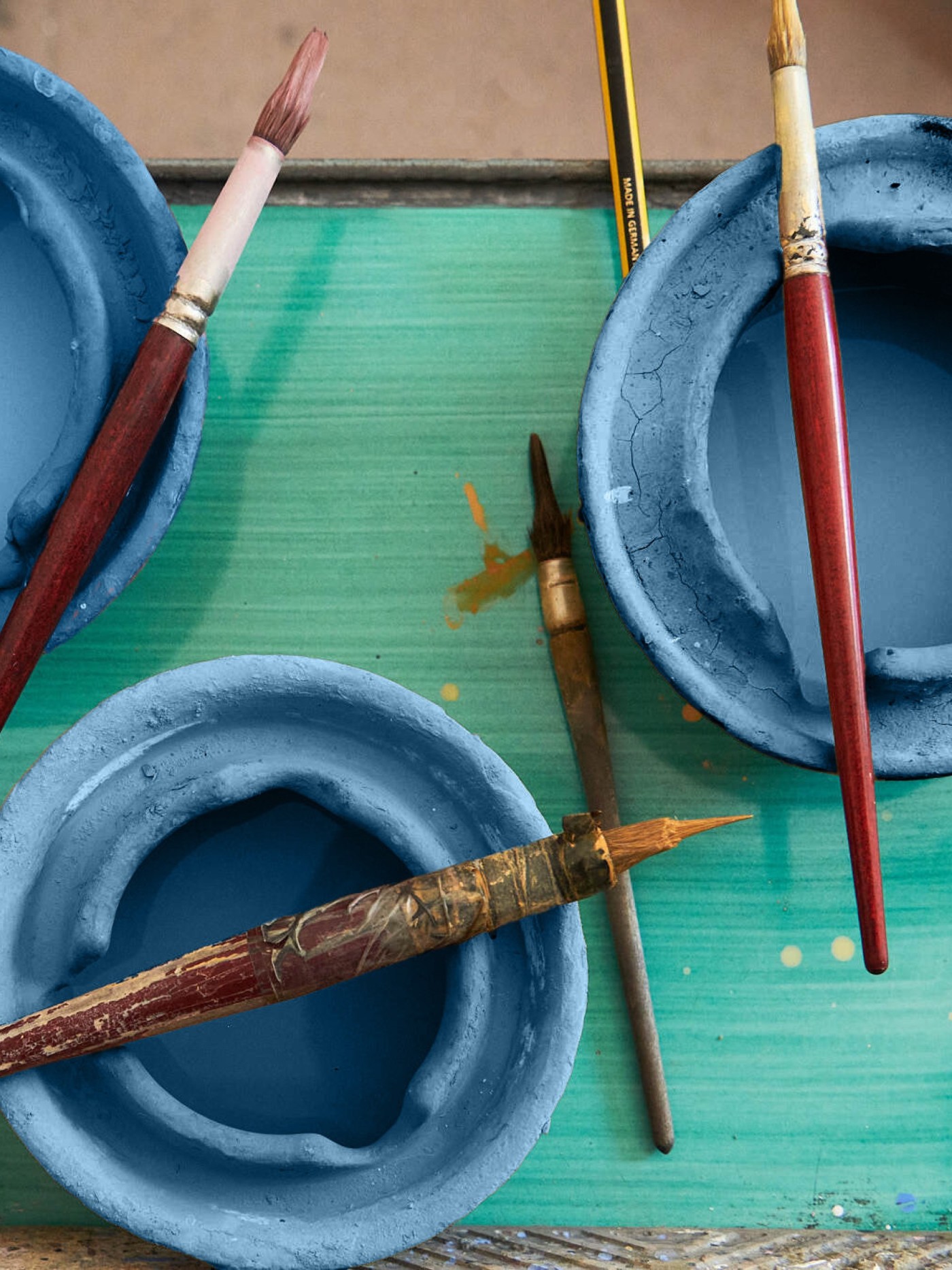 a table with blue bowls and paint brushes on it.