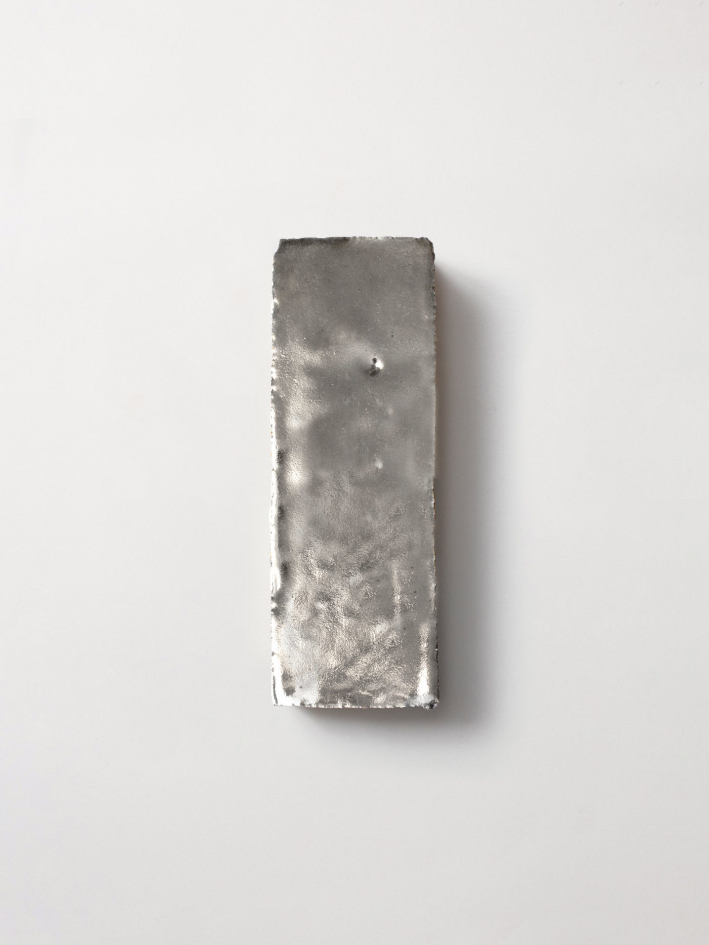 a metallic, rectangular tile on a white surface.