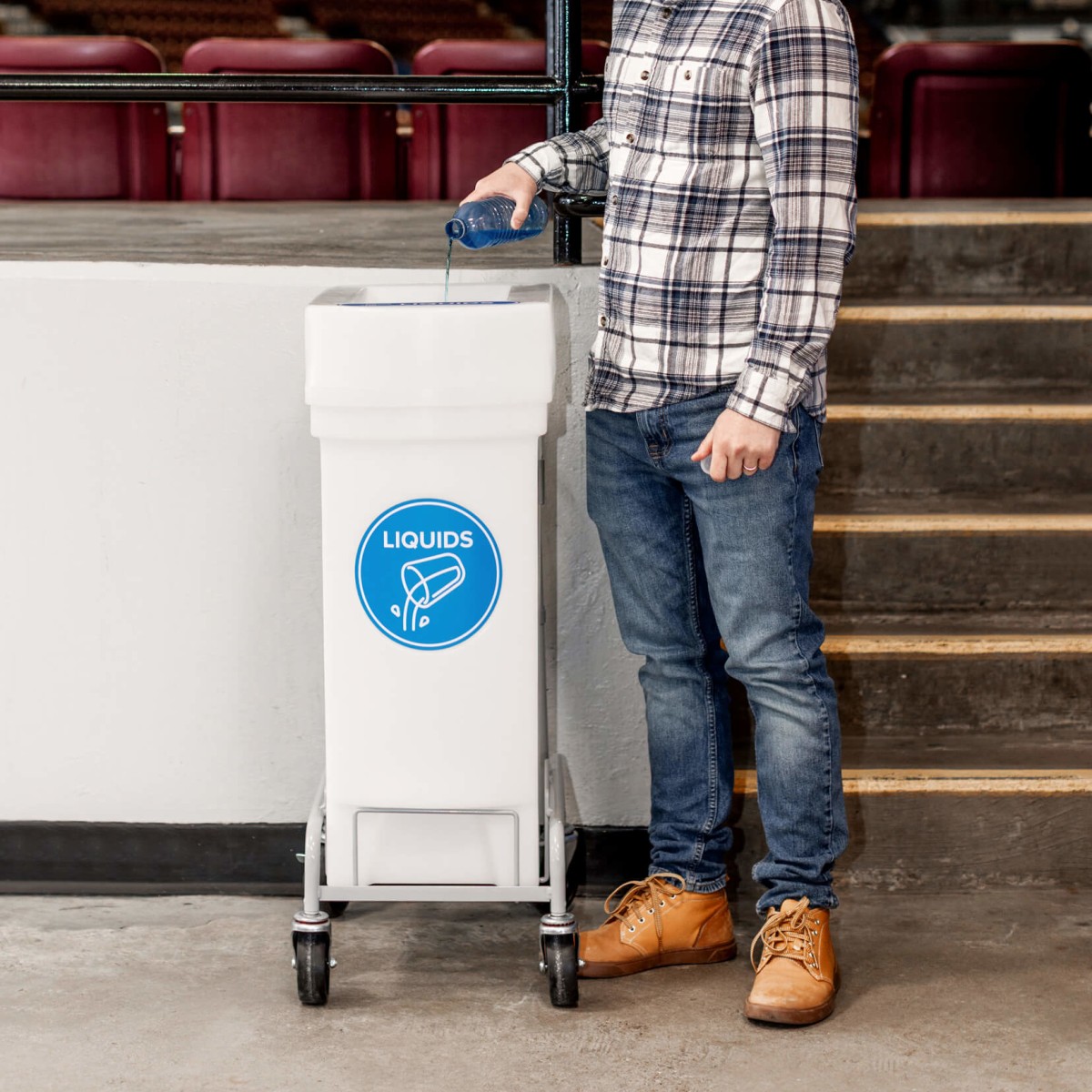 man emptying water into liquid collection bin at a concert venue