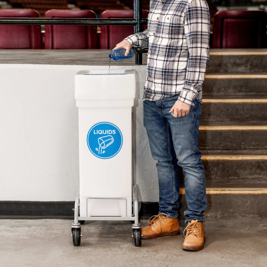 man emptying water into liquid collection bin at a concert venue
