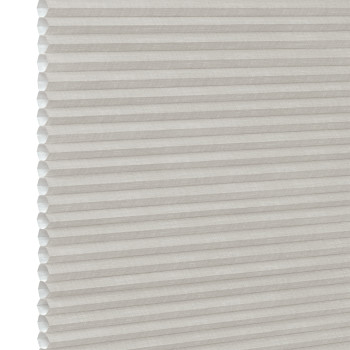 White pleated honeycomb (cellular) blind, fully lowered with visible hexagonal cells at left edge, closed and softly filtering light, close-up interior view with neutral lighting.