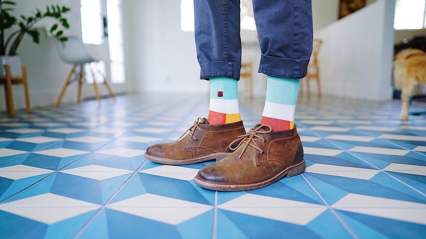 a man wearing colorful socks on a blue and white tile floor.