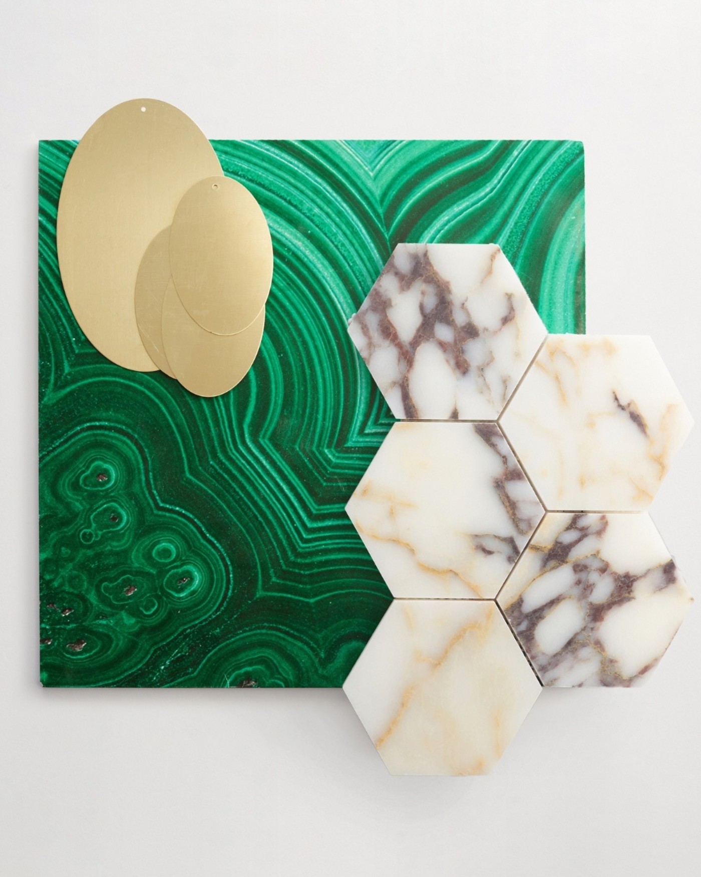 marble hex tiles, a gold metal tile and a green patterned tile on a white surface.