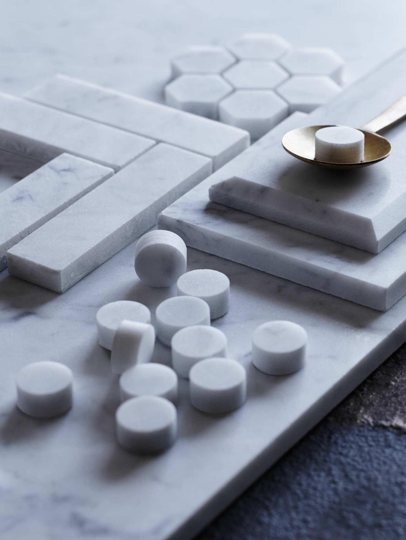 a tray of marble tiles and a spoon on a table.