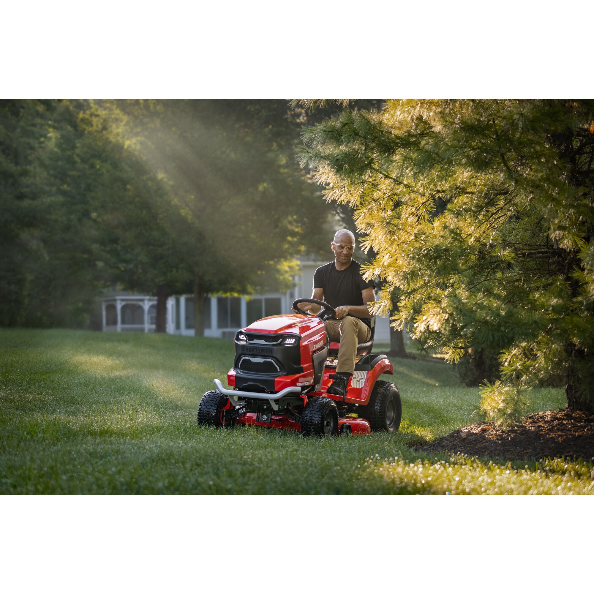 CRAFTSMAN Battery-Powered Riding Mower mowing background with woods and fence in background