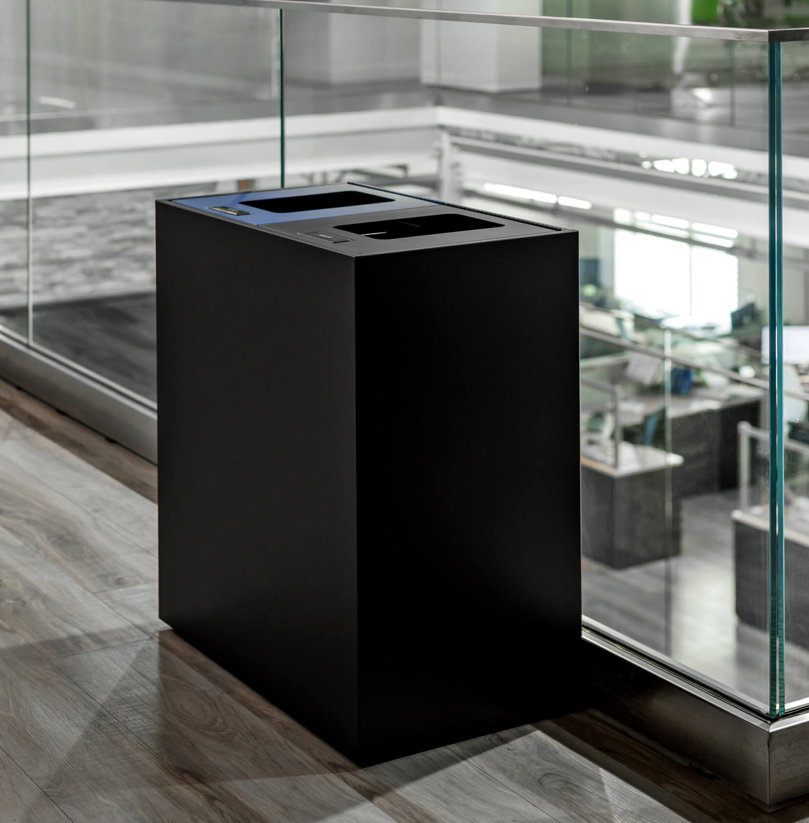 black powder coated steel recycling and trash bin in a modern office environment