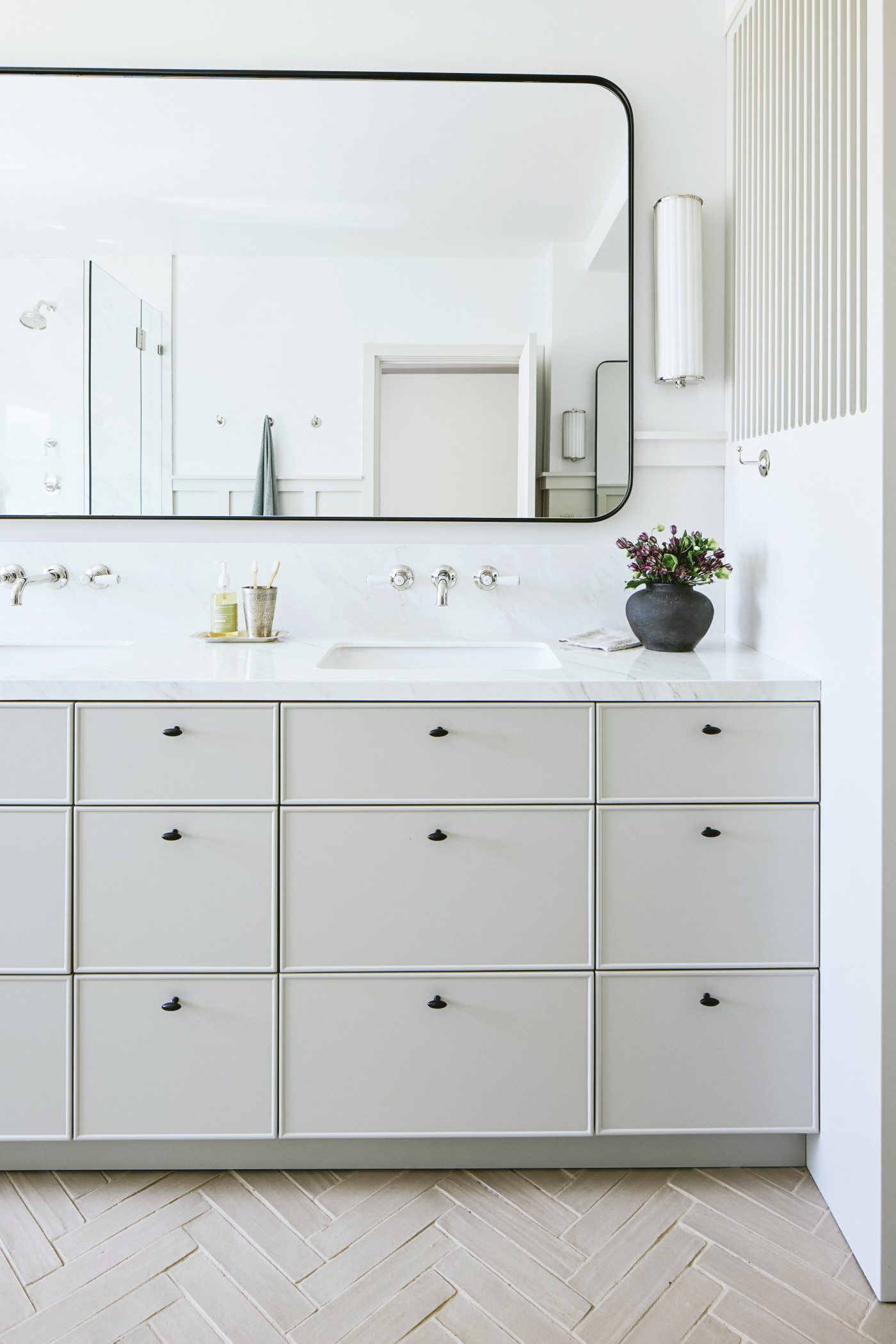 a bathroom with a white tiled floor, white cabinets and a large mirror.