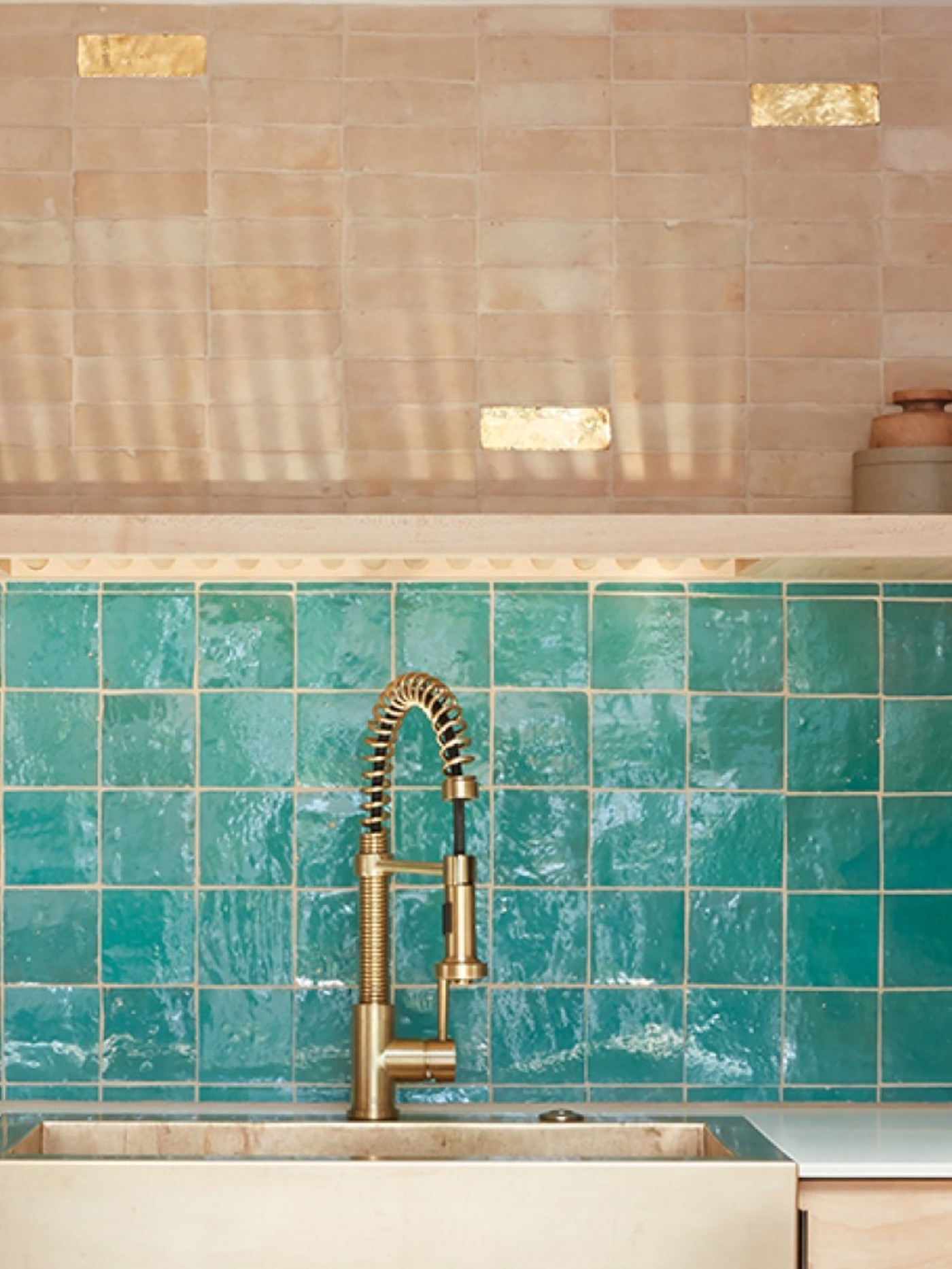 a kitchen with turquoise backsplash tiles and a gold sink.