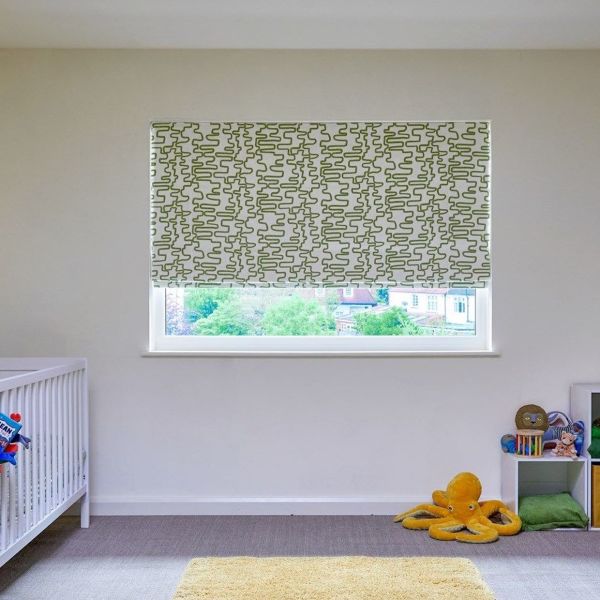 Patterned roller blind (white with green squiggly pattern) lowered over window, filtering daylight into a simple nursery with a white crib at left and a plush orange octopus by a toy shelf.