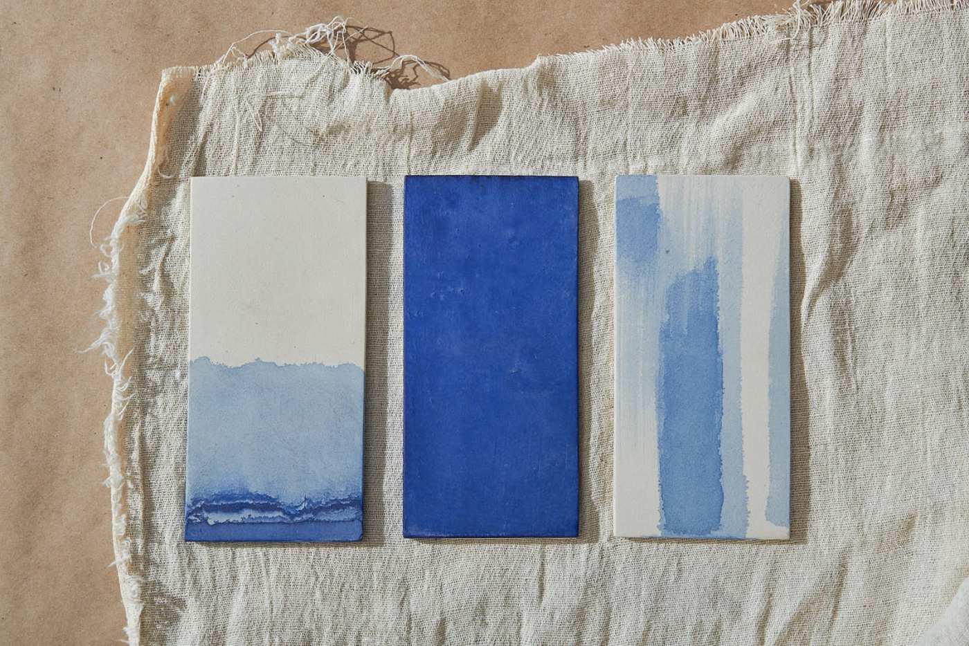 three blue and white tiles on a piece of cloth.