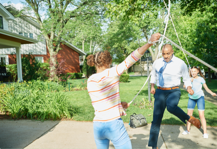 A man in a tie playing double dutch with two kids.