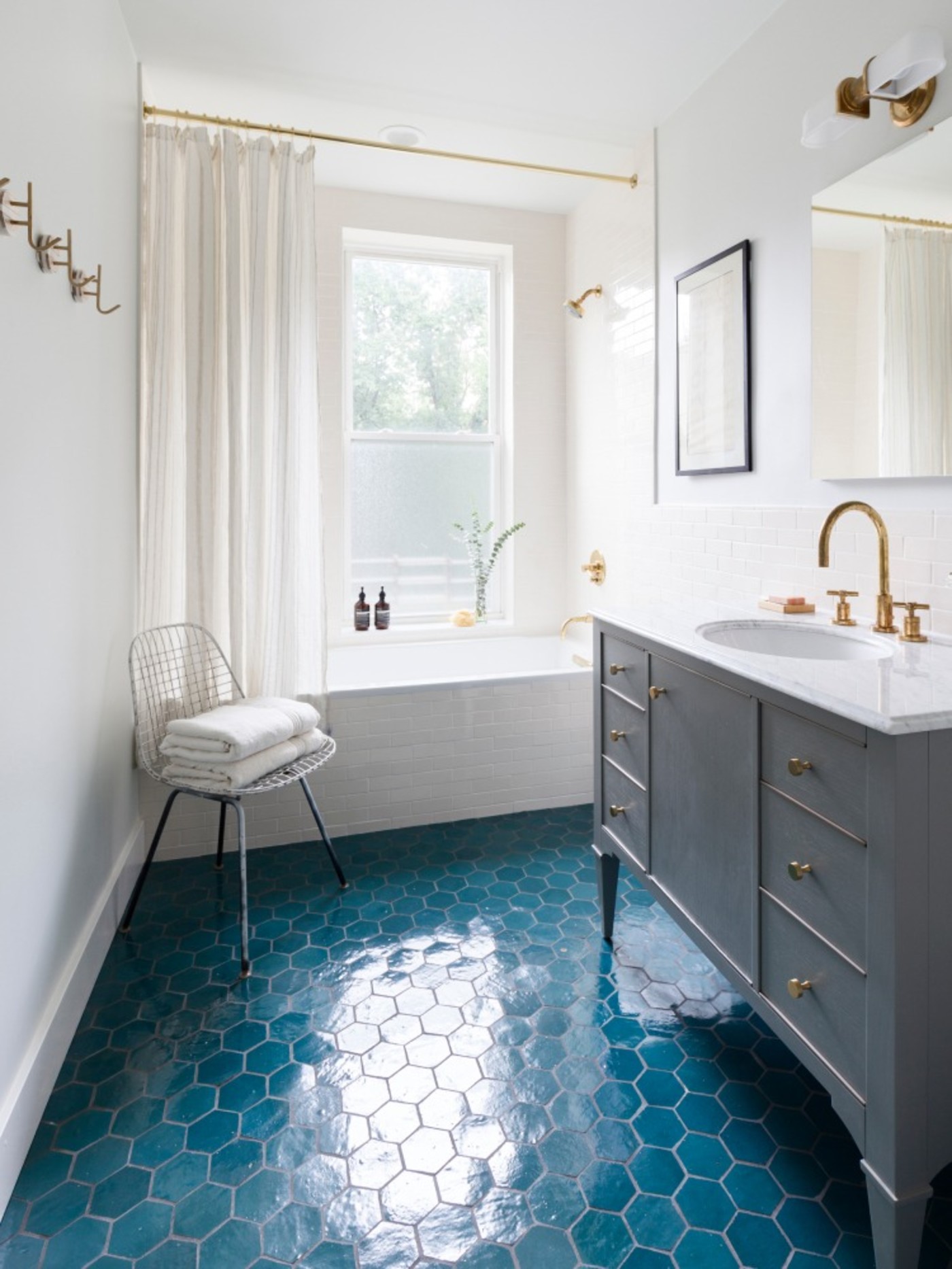 a bathroom with a blue tile floor and gold fixtures.