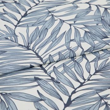 Blue botanical-print fabric (fine woven textile with navy stems and pale blue elongated leaves) folded and layered, edges overlapping; close-up view on a white surface with soft, diffused lighting.