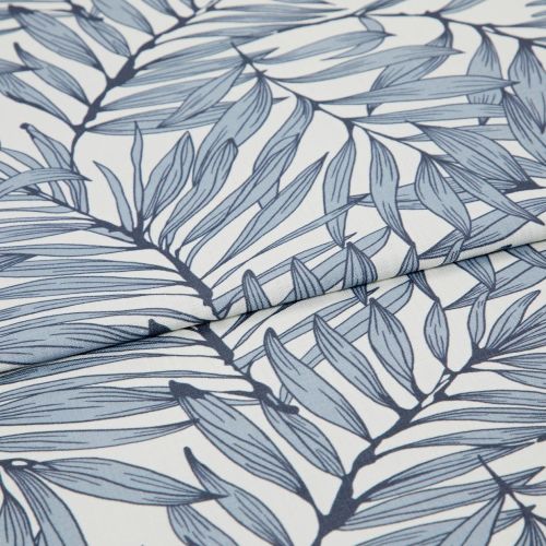Blue botanical-print fabric (fine woven textile with navy stems and pale blue elongated leaves) folded and layered, edges overlapping; close-up view on a white surface with soft, diffused lighting.