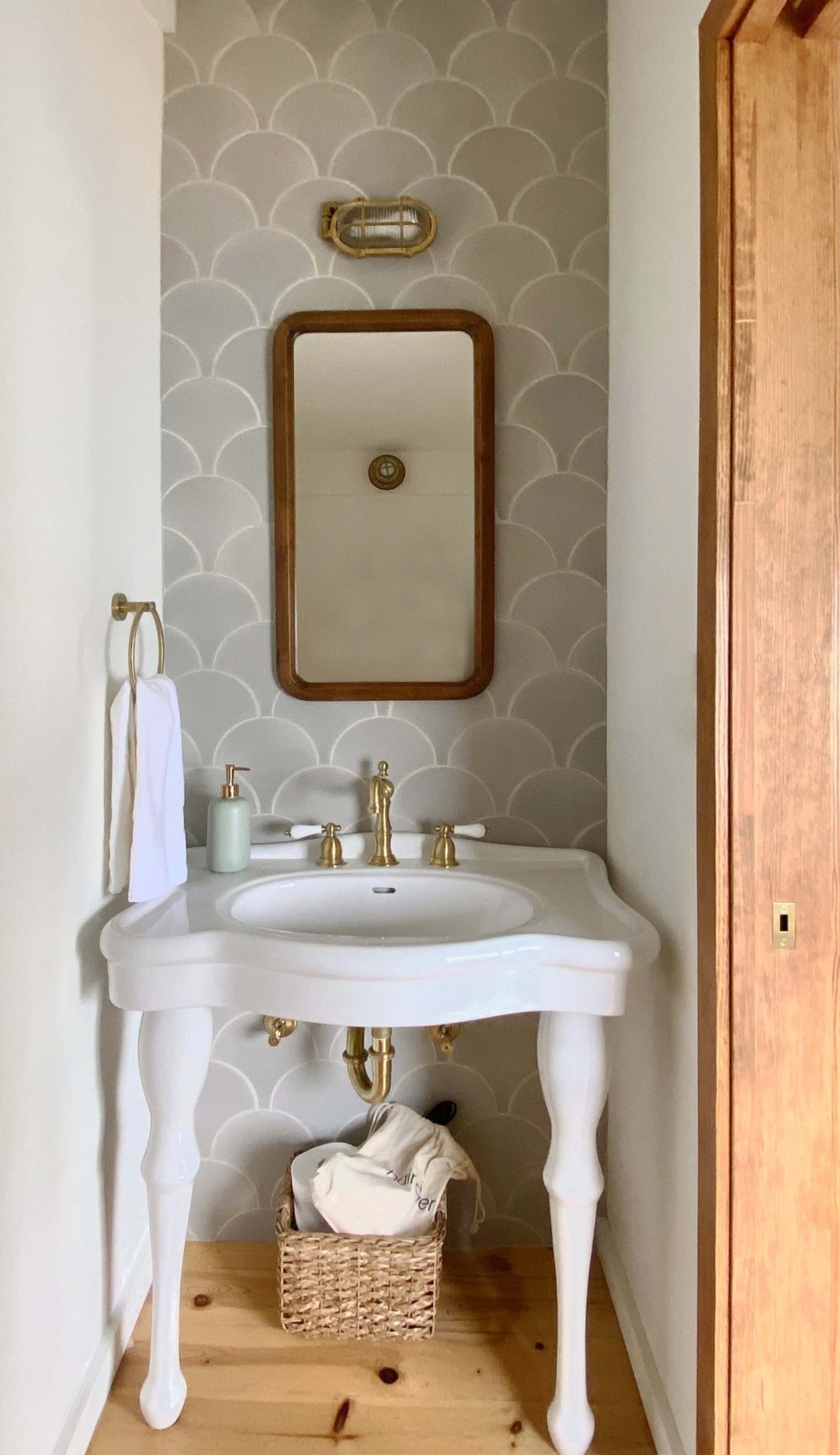 a bathroom with a sink, mirror, and a grey tiled wall.