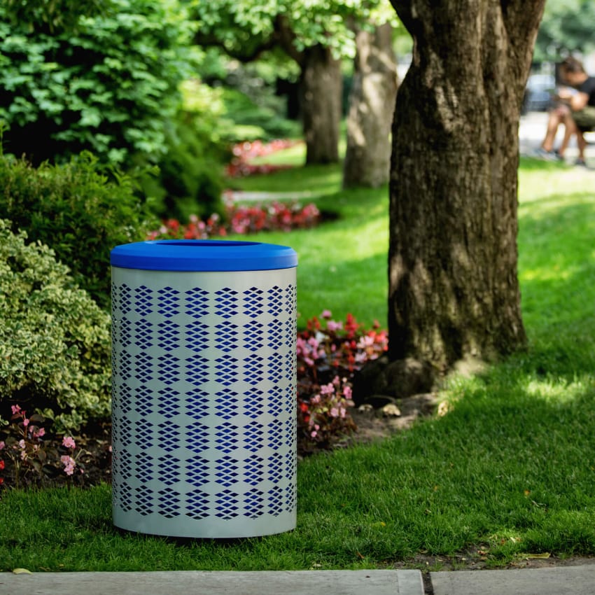 silver powder coated steel recycling bin with a blue liner and blue lid sitting on the grass at a town park area