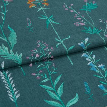 Embroidered teal fabric with vertical stitched wildflower stems — folded once across the middle, showing multicolored threadwork — close-up view with even, soft lighting emphasizing texture.