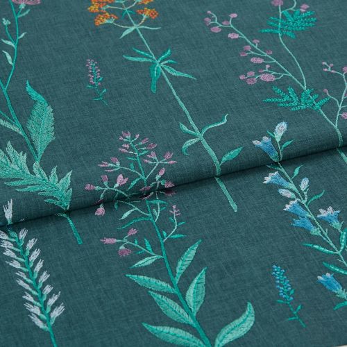 Embroidered teal fabric with vertical stitched wildflower stems â€” folded once across the middle, showing multicolored threadwork â€” close-up view with even, soft lighting emphasizing texture.
