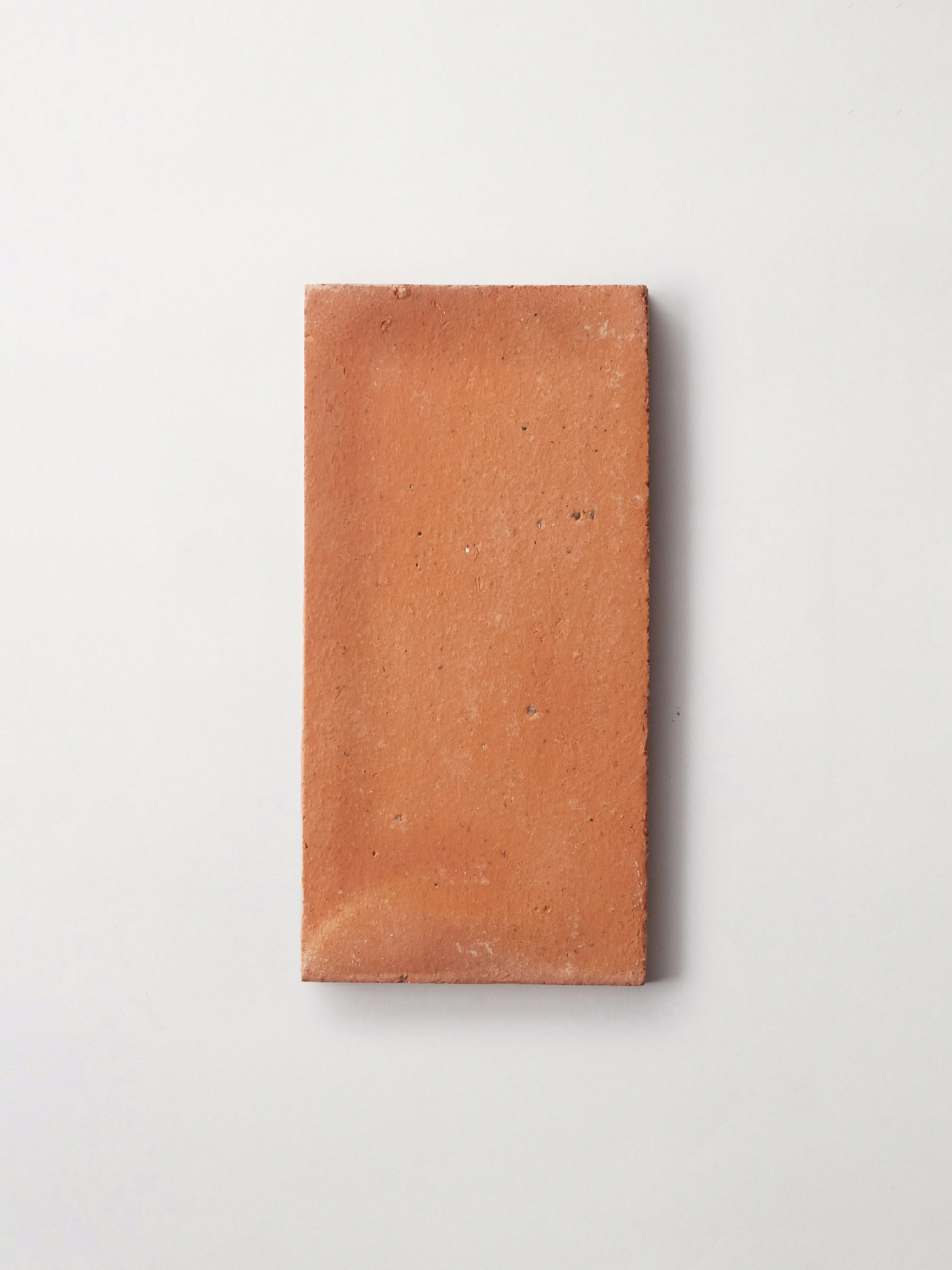 a rectanglular piece of terracotta tile on a white surface.