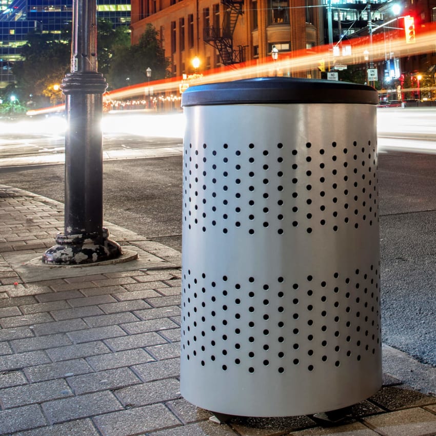 closeup of a metal and plastic multi-stream waste and recycling container outside on a busy city sidewalk