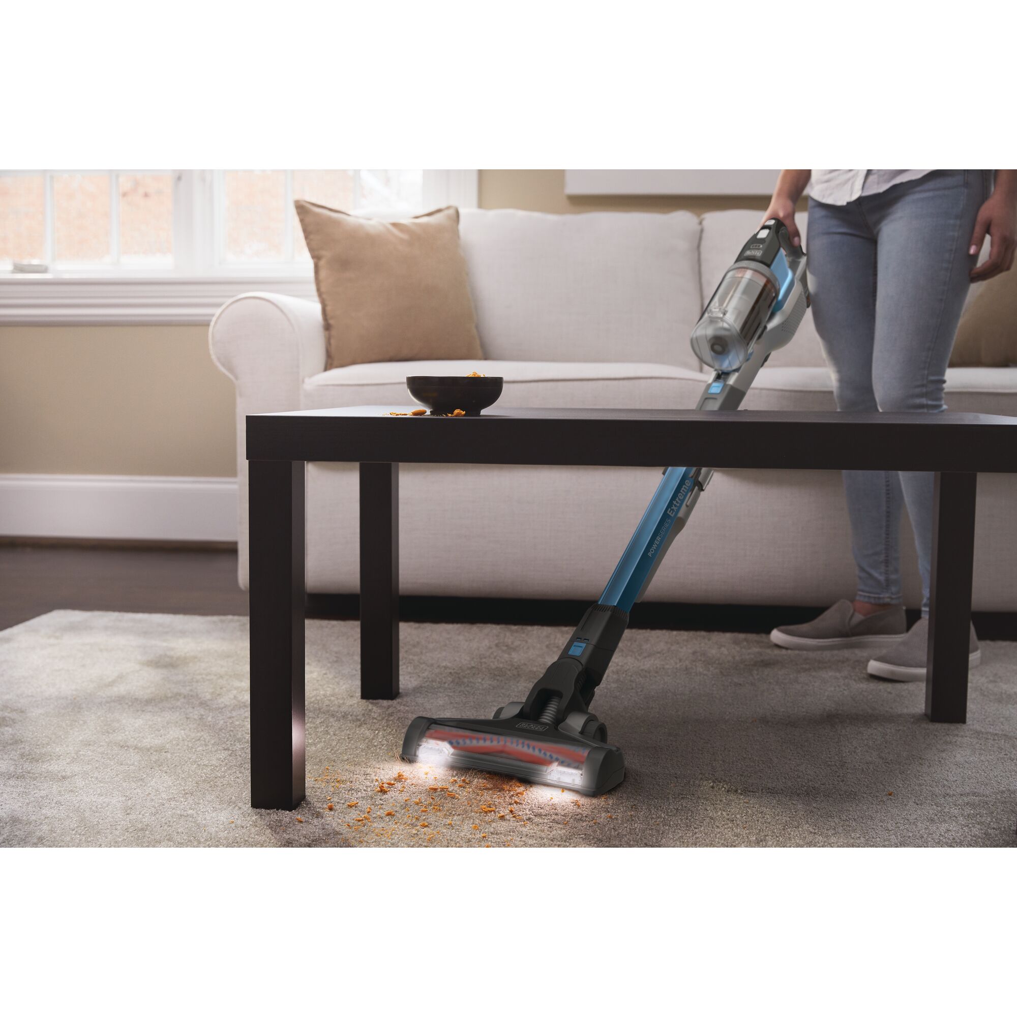 POWERSERIES Extreme Cordless Stick Vacuum Cleaner being used to clean dirt on a carpet by a person.