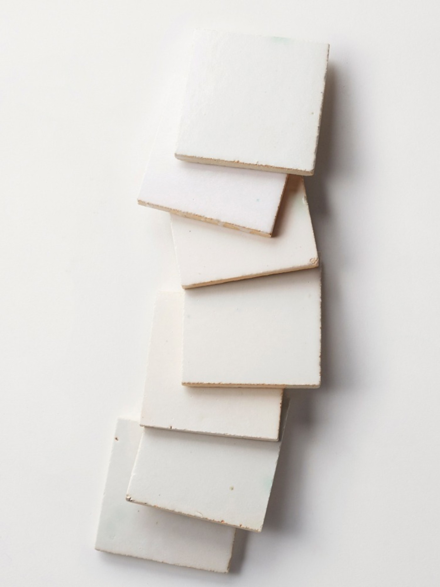 a stack of square white tiles on a white surface.