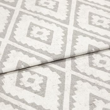 Woven rug with repeating gray diamond-and-zigzag pattern, shown folded once across the center; textured fabric lies flat in soft, even studio lighting, close-up detail view.