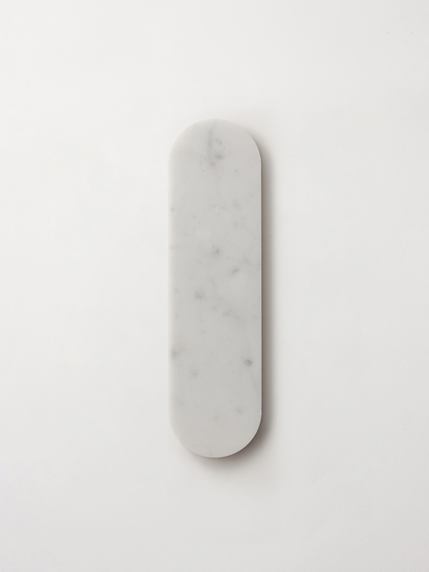 an oval white marble tile on a white surface.