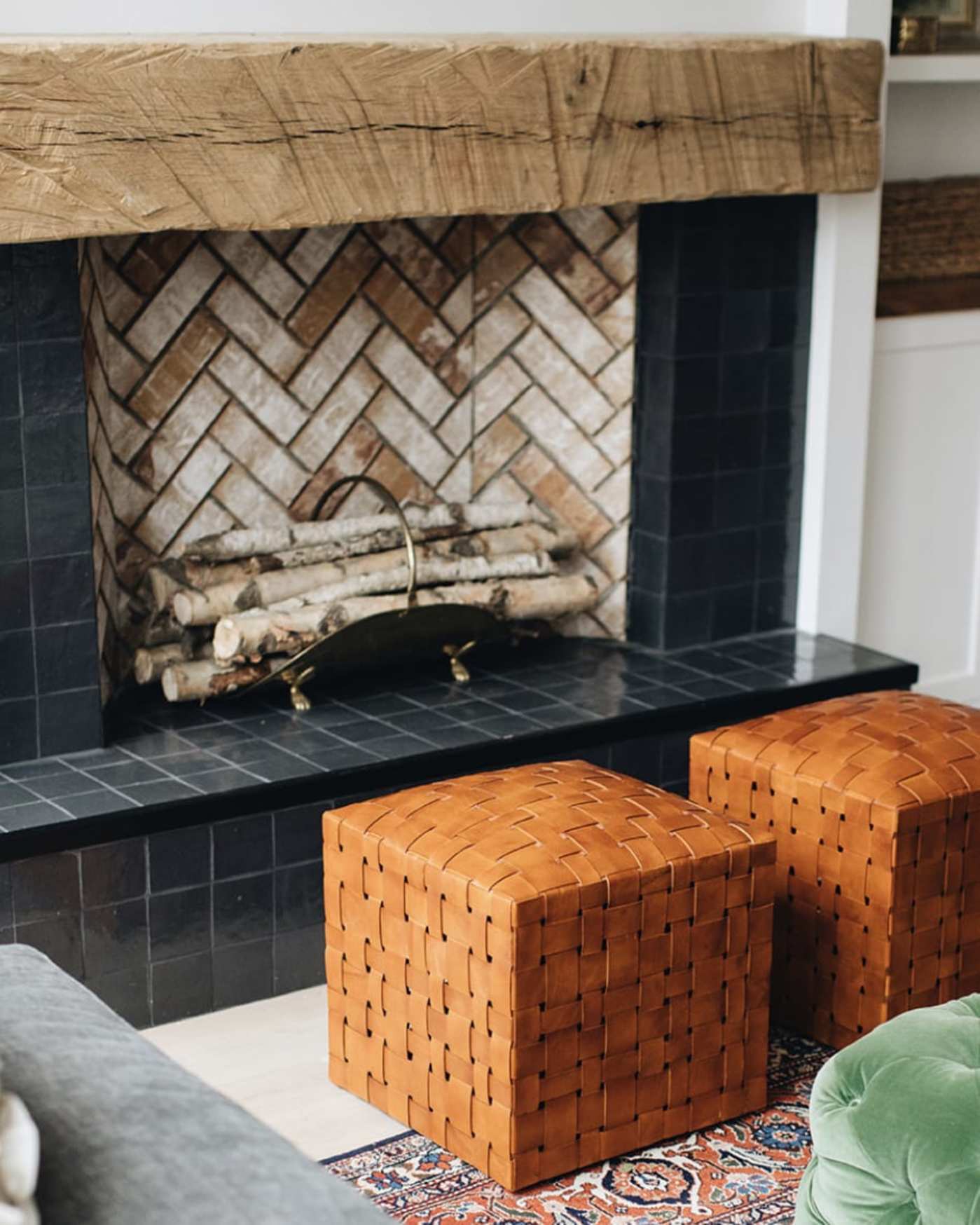 a living room with a fireplace and orange ottomans.