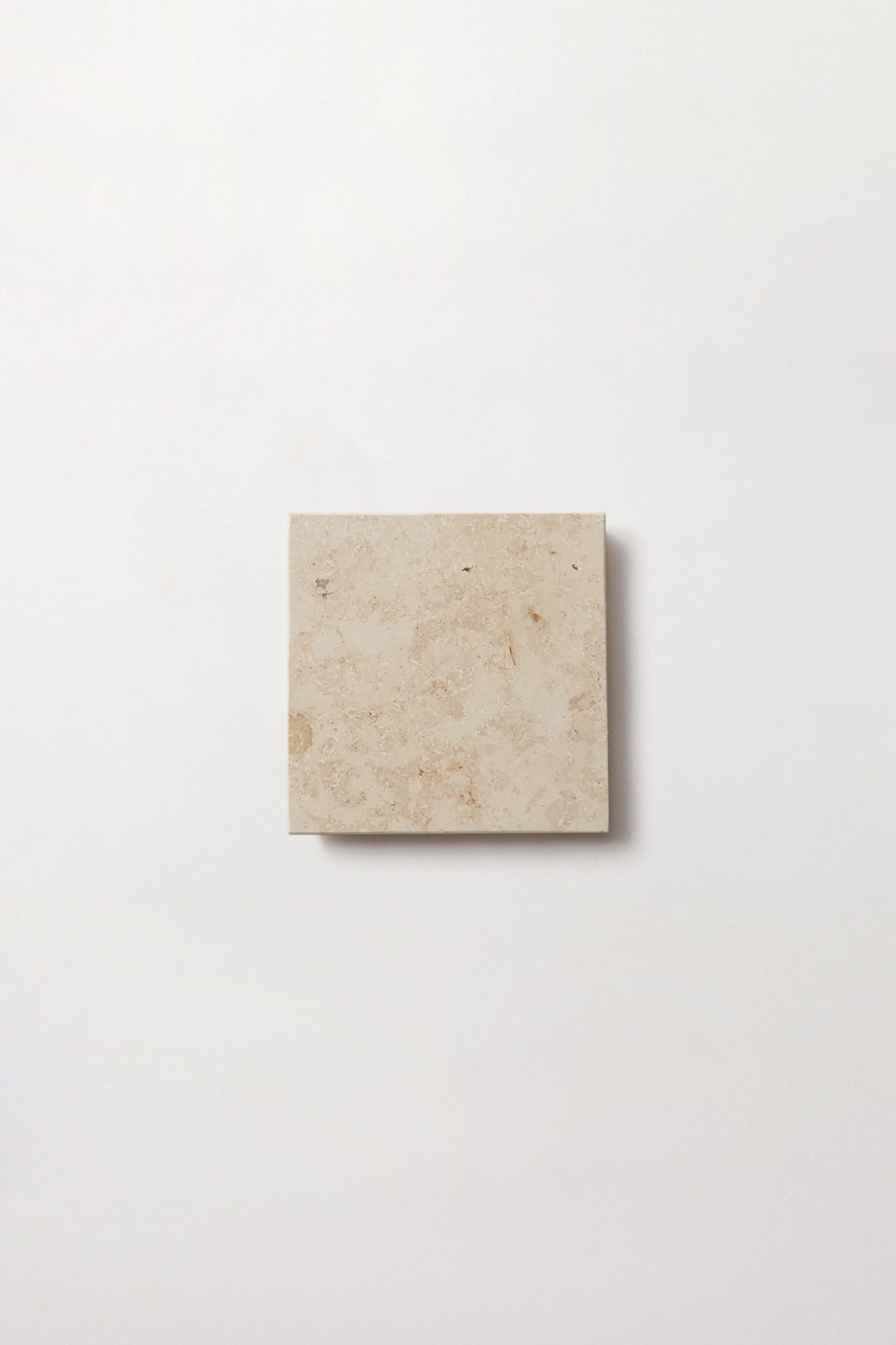 a square limestone tile on a white surface.