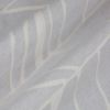 Pale gray curtain fabric with white abstract leaf pattern, draped in soft diagonal folds; fabric appears slightly textured and creased, shown in a close-up under soft, neutral indoor lighting.