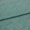 Speckled green fabric (small irregular white dots) folded across center, creating a shallow overlapping crease; close-up on a flat, evenly lit textile sample.